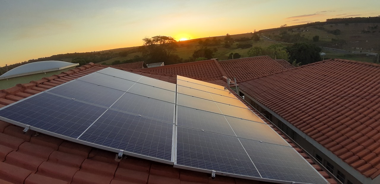 Sistema fotovoltaico em telhado residencial ao pôr do sol
